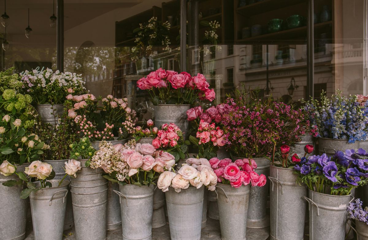 Metal buckets of pink garden roses and spray roses outside a flower shop