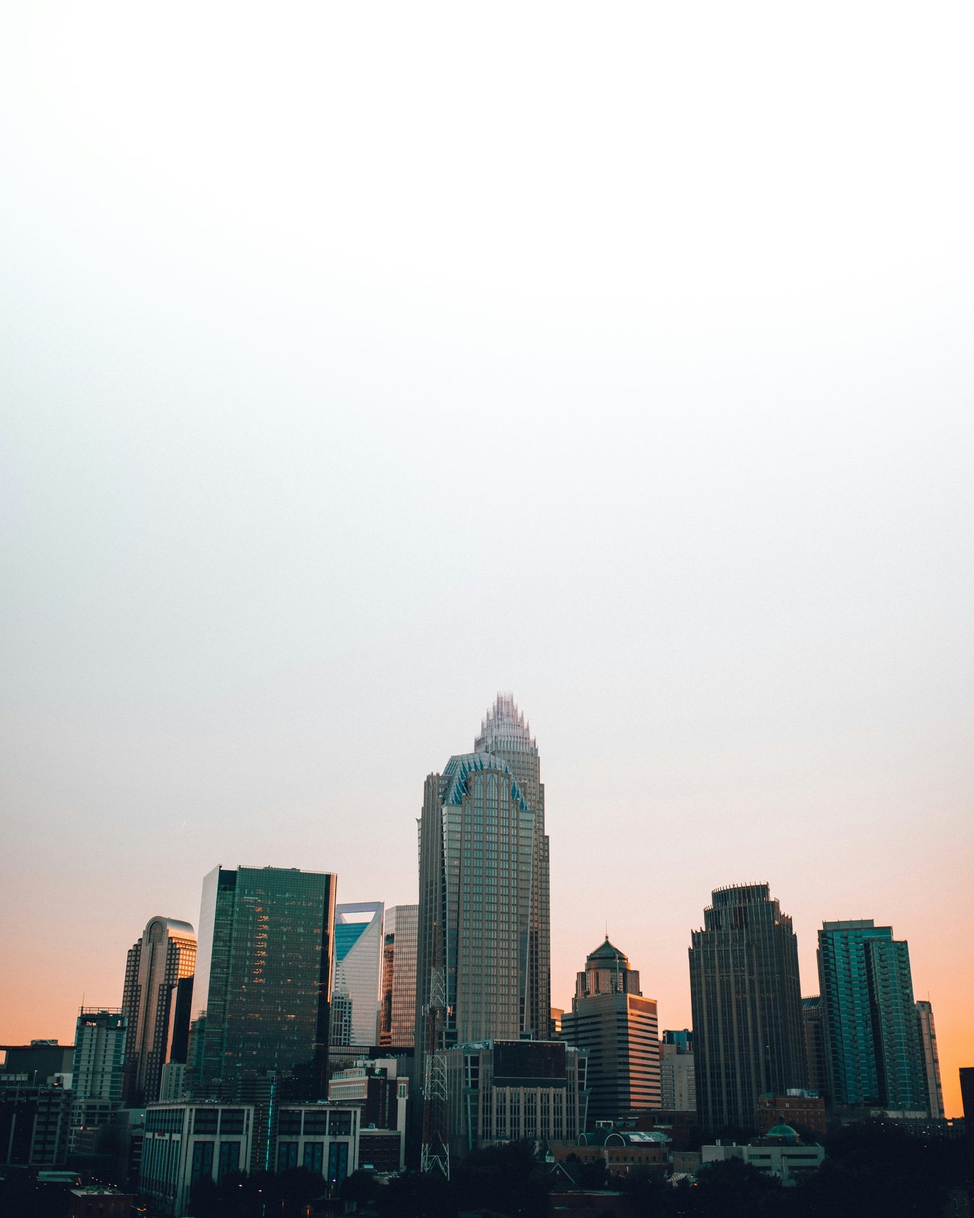 The Uptown Charlotte skyline at dusk under a pale peach sky